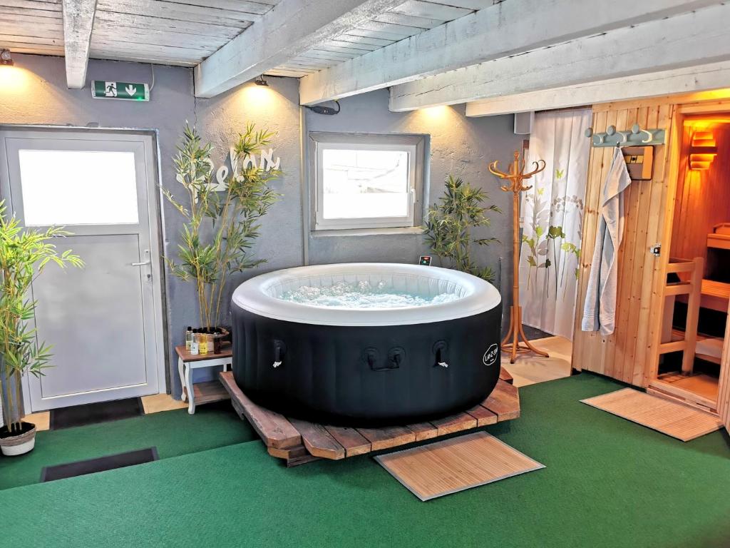 uma grande banheira num quarto com piso verde em Wellness zur Alleinnutzung mit Ferienwohnung und Fitnessbereich - fitSPA em Sulz am Neckar