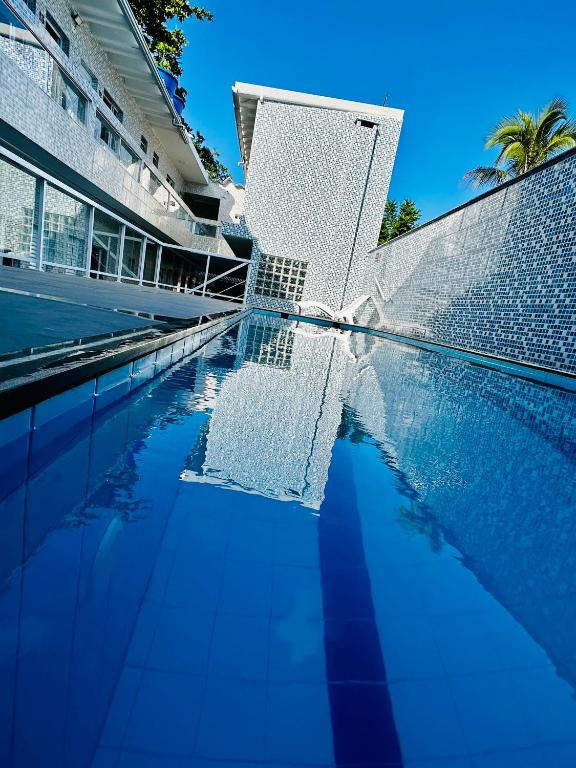 a swimming pool with blue water in front of a building at Pousada Pazzini in Guarujá