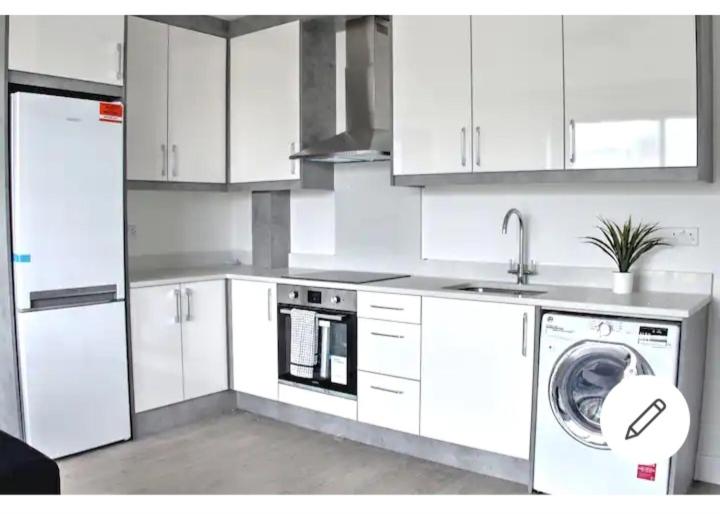 a kitchen with white cabinets and a washing machine at Lovely 2-bedrooms with free parking in Canvey