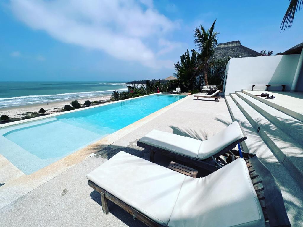a swimming pool with a lounge chair next to the ocean at Villa ALDIANA in Cap Skirring