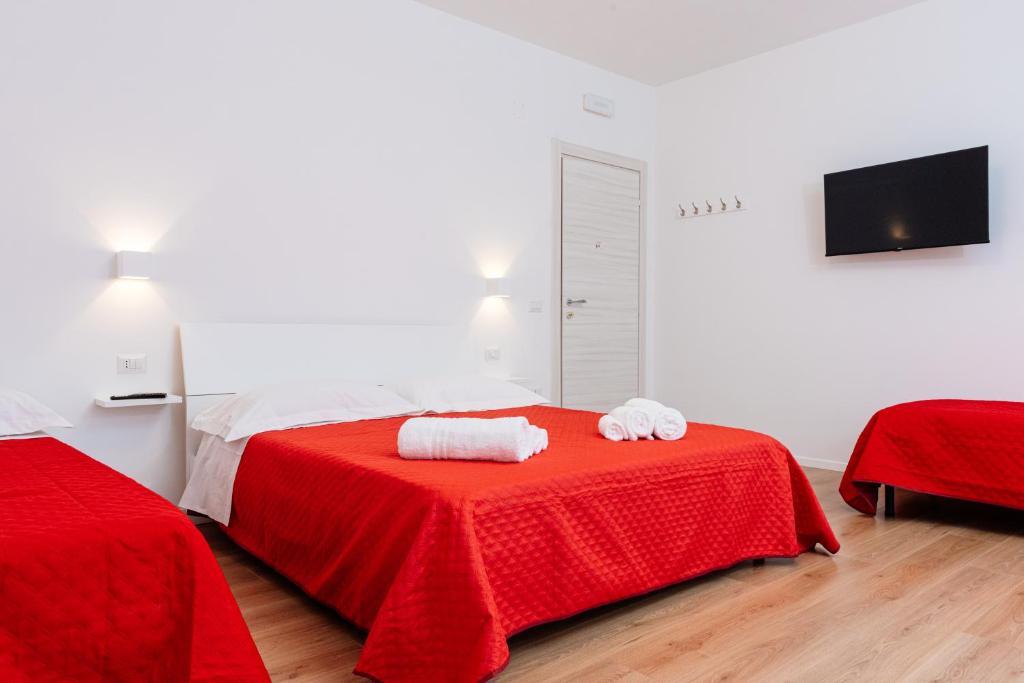 1 dormitorio con 1 cama roja y 2 toallas en una mesa en La Casa di Ambra en Porto Torres