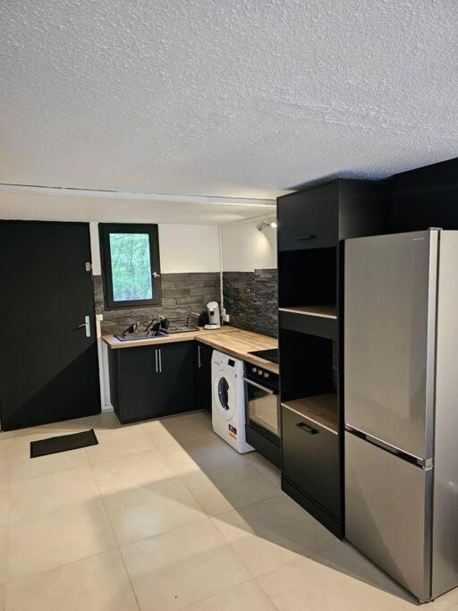une cuisine avec des armoires noires et un réfrigérateur en acier inoxydable dans l'établissement appartement 50m2 village vacances, à Arles