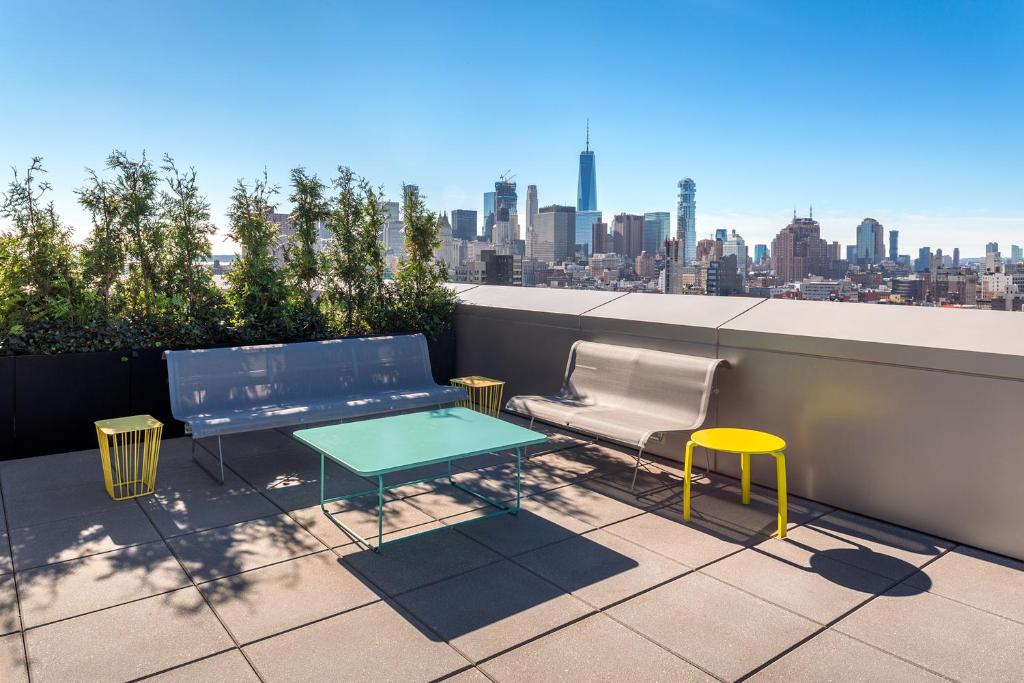 een tafel en stoelen op een balkon met een skyline van de stad bij Hotel Indigo Lower East Side New York in New York