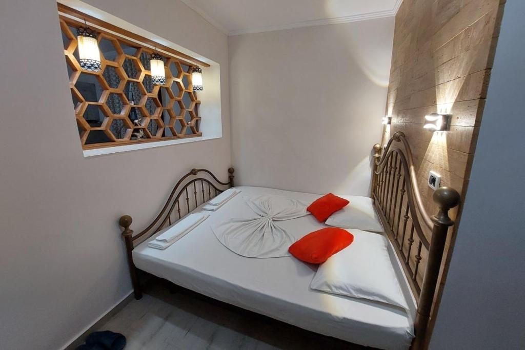 - une petite chambre avec un lit et deux oreillers orange dans l'établissement villa Heljos apartaments, à Vlorë