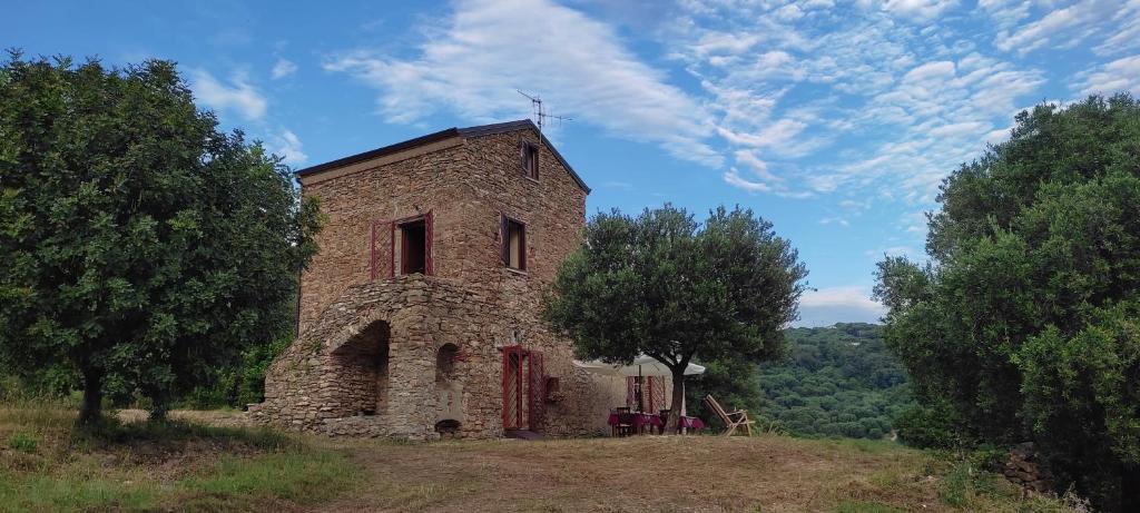 an old stone building on a hill with trees at La Formica in Ascea