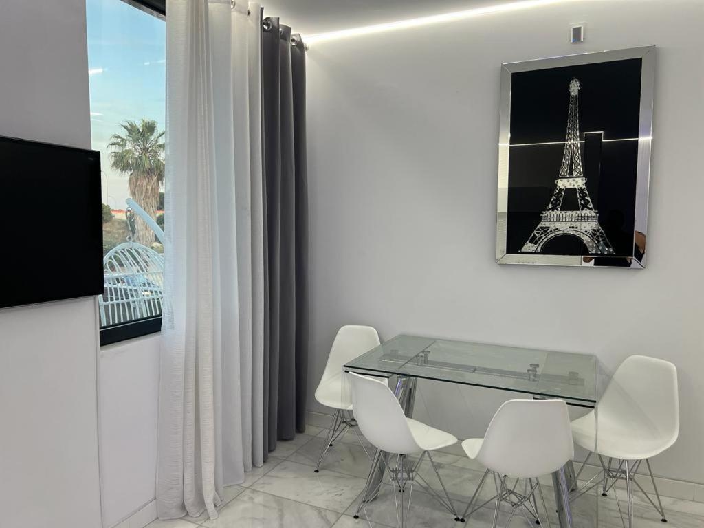 comedor con mesa de cristal y sillas blancas en DeLuxe House Valencia, en Valencia