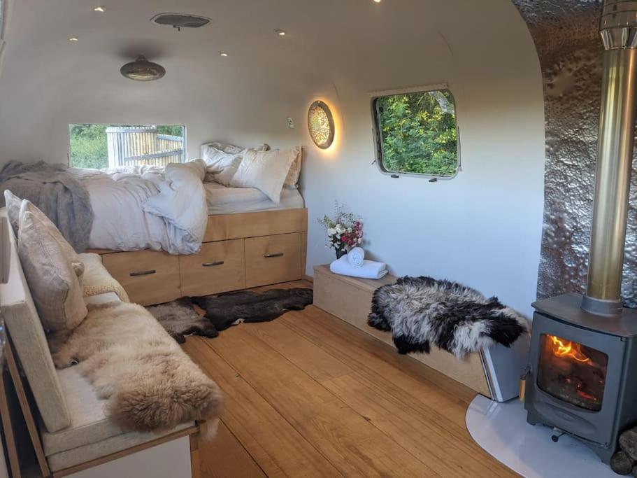 a bedroom with a bed and a wood stove at Airstream, vintage American caravan & Hottub in Ashburton