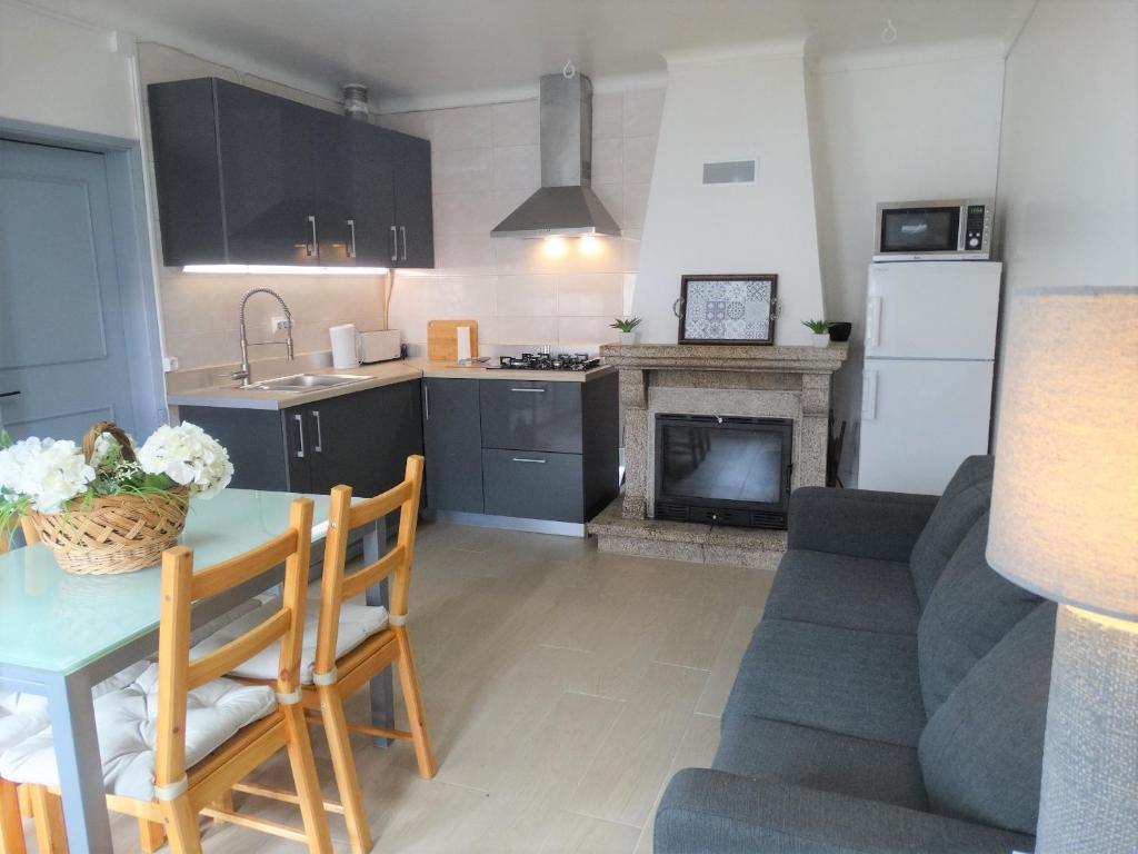 a kitchen and living room with a table and a fireplace at Casa Sardinha 