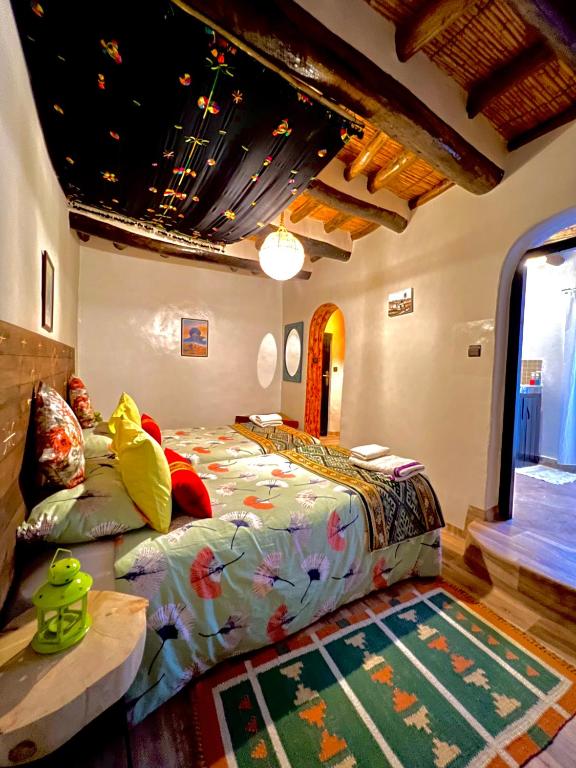 a bedroom with a large bed and a table at Kasbah El Hajja in Aït Benhaddou