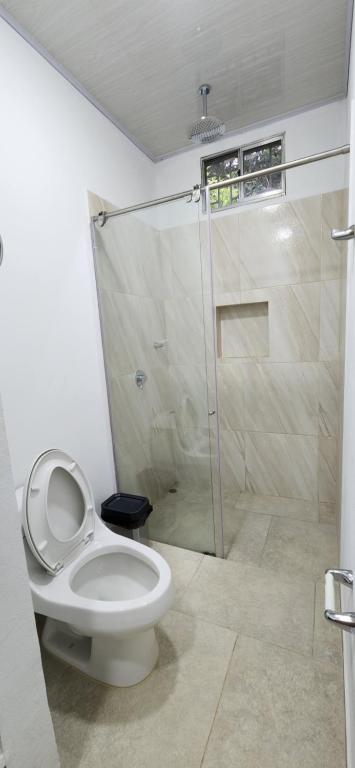 uma casa de banho com um WC e uma cabina de duche em vidro. em Villeta Casa de Campo caracoli spa em Villeta