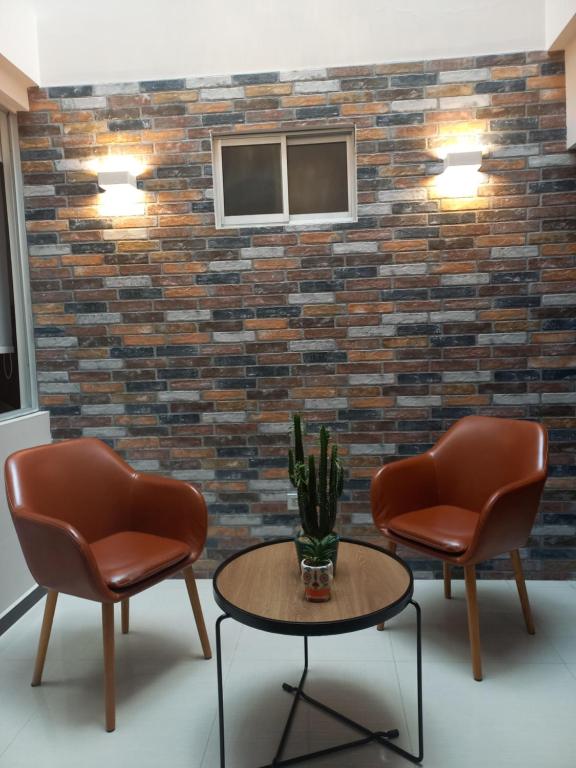 two chairs and a table in front of a brick wall at HOTEL SANTORI in Pasto