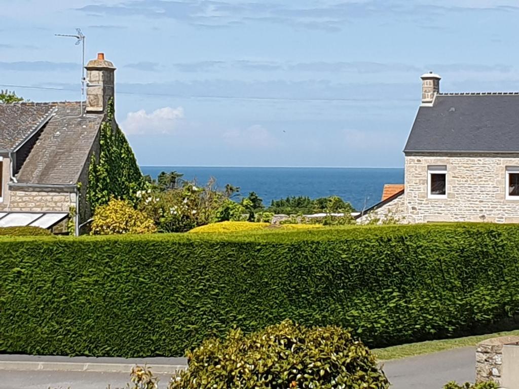 a house with a hedge in front of the ocean at Le relais du phare in Gatteville-le-Phare