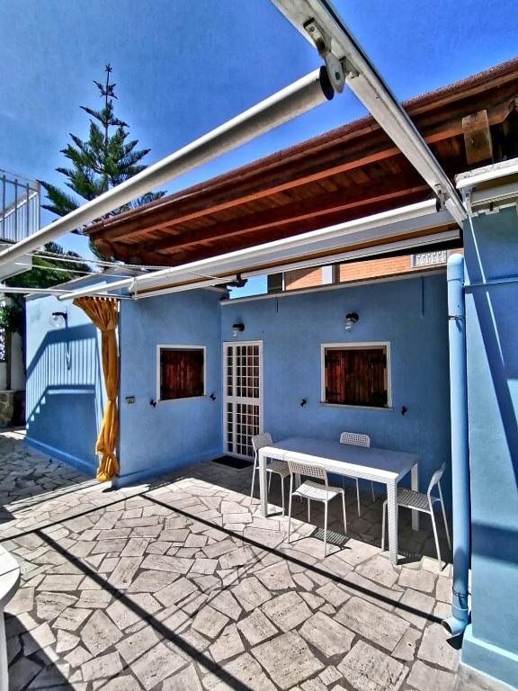 a patio with a white table and a blue wall at La casa delle sirene sul mare di Anzio in Anzio