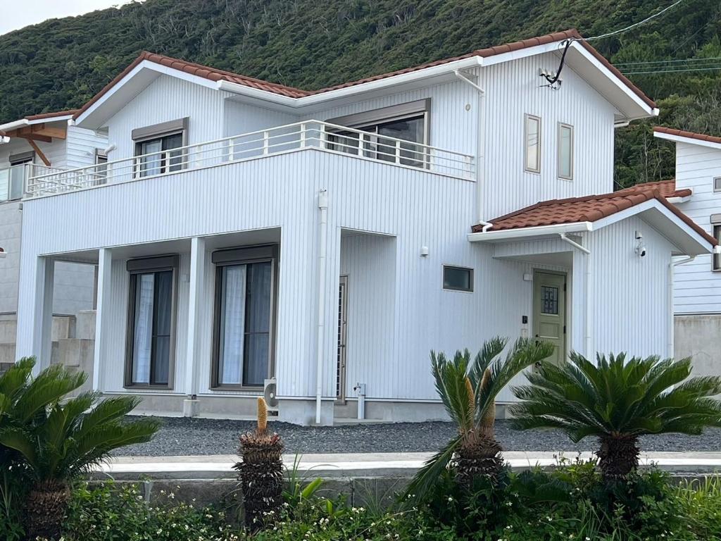 een wit huis met palmbomen ervoor bij KUSUMARU - Vacation STAY 13707v in Ōkachi