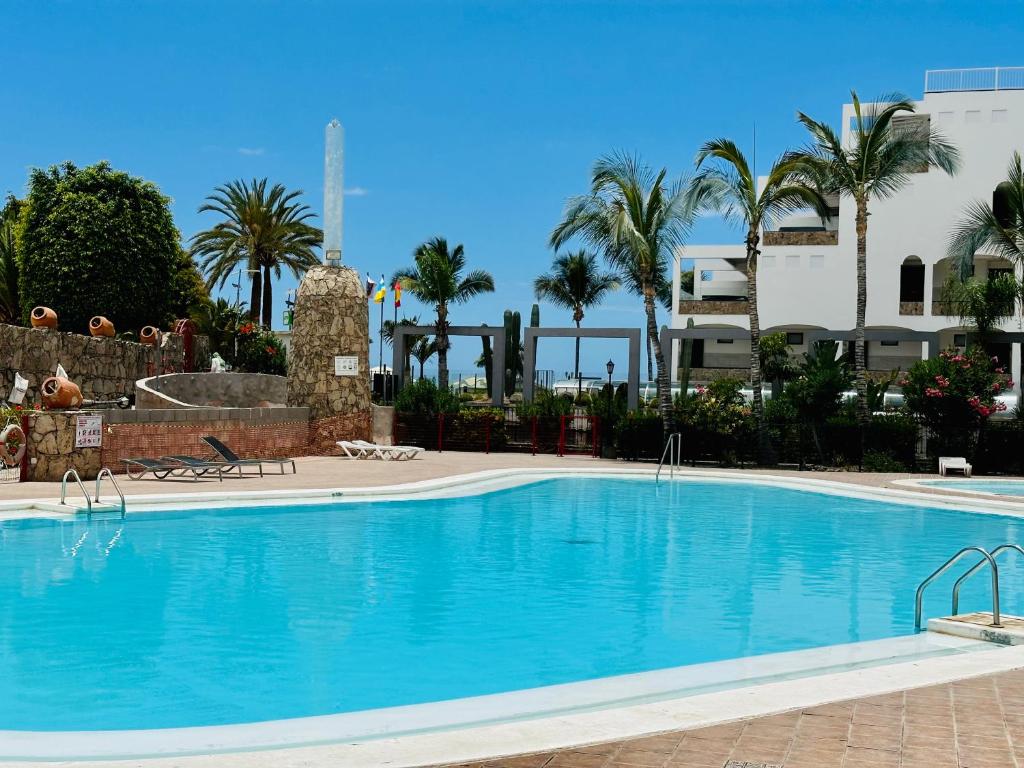 een groot zwembad met palmbomen en een gebouw bij Playa del Cura in Playa del Cura