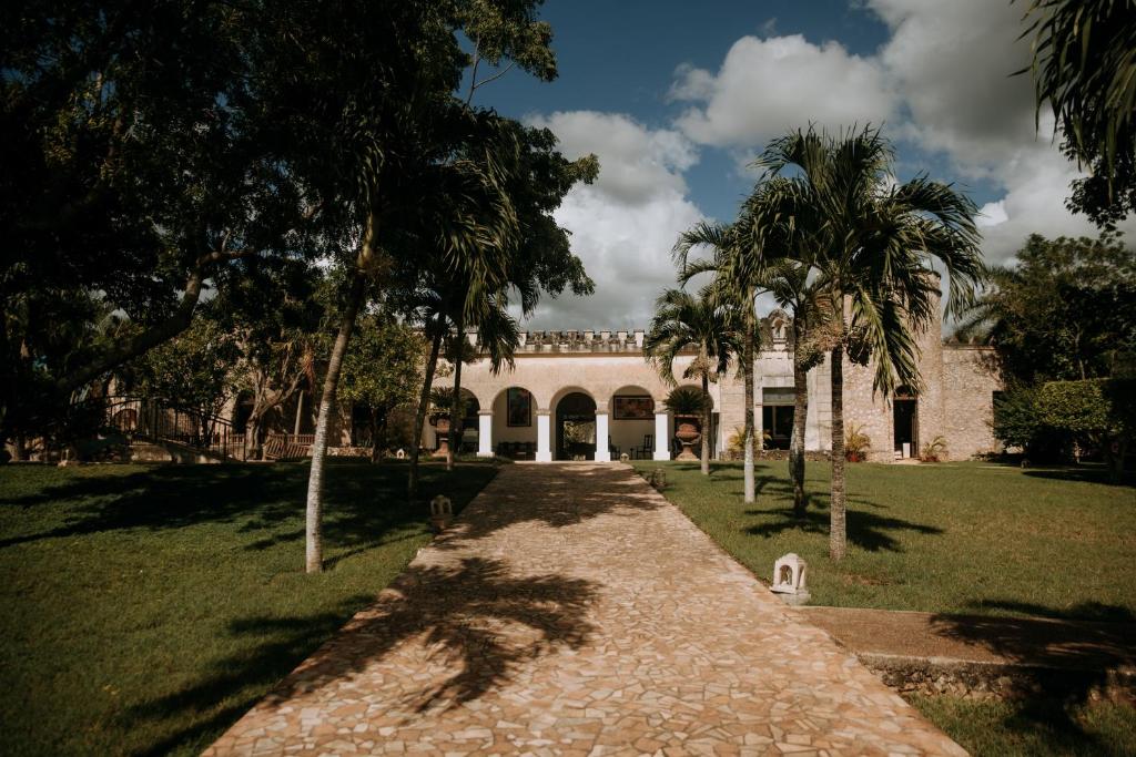a pathway leading to a building with palm trees at Hacienda Kaan Ac in Valladolid