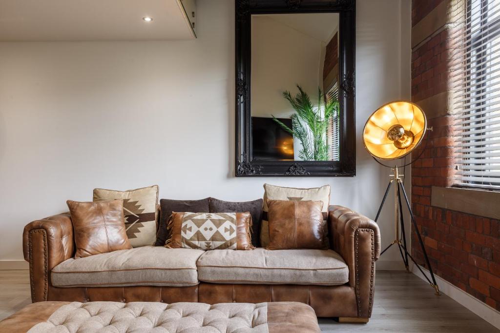 a living room with a brown couch and a mirror at Stunning Designer Penthouse - 85'' Cinema TV! in Bradford