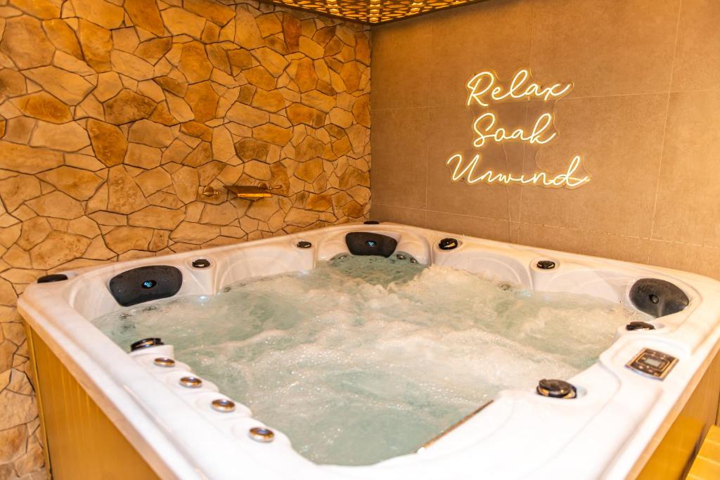 a hot tub in a bathroom with a stone wall at Alexandras Palace in Bradford