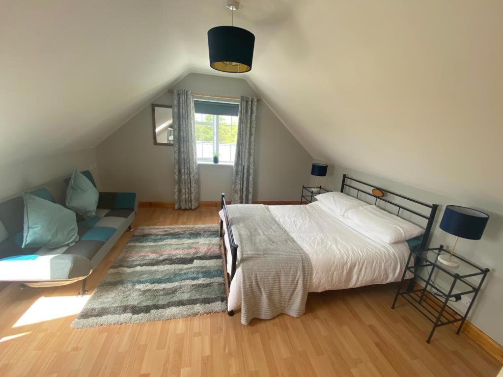 een slaapkamer met een bed en een bank op zolder bij Loch Nuala in Galway