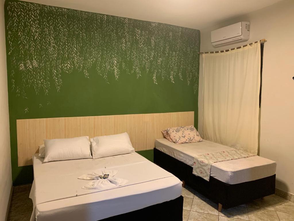 2 camas en una habitación con una pared verde en Bálsamo Hotel Marília, en Marília