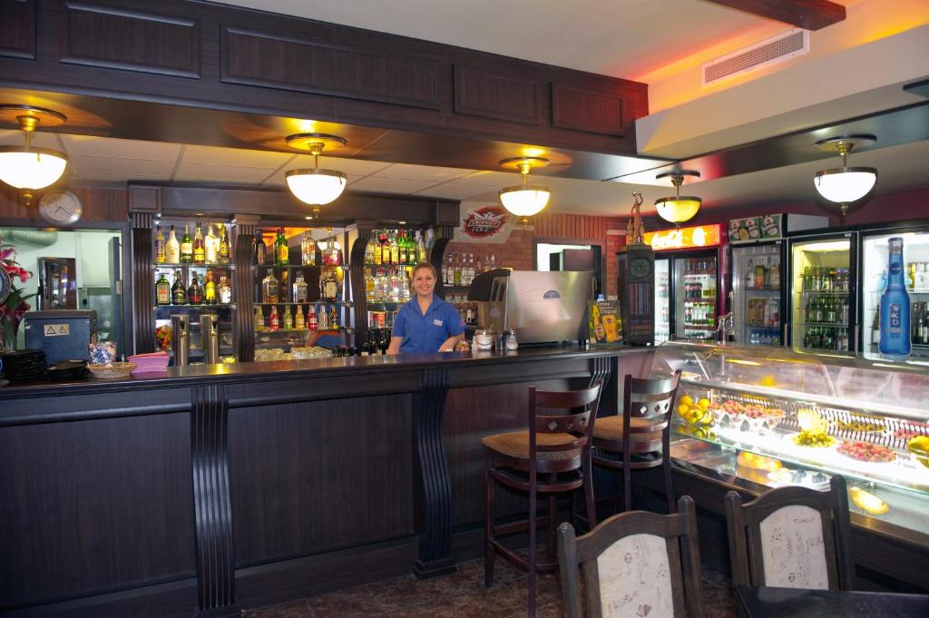 a man standing at a bar in a pub at Lotus Family Hotel - Free Parking in Sunny Beach