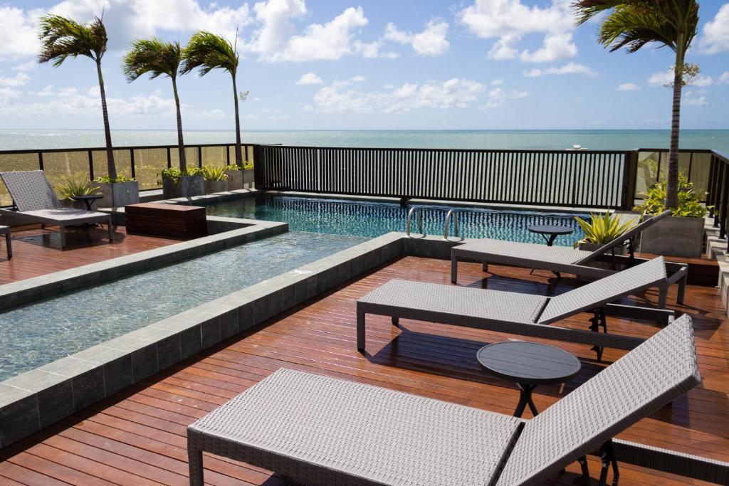 a swimming pool with tables and chairs on a deck at Arpoar Suítes 330 in João Pessoa