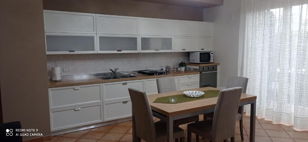 una cocina con armarios blancos y una mesa con sillas. en RITA LITTLE HOUSE, en Mascali