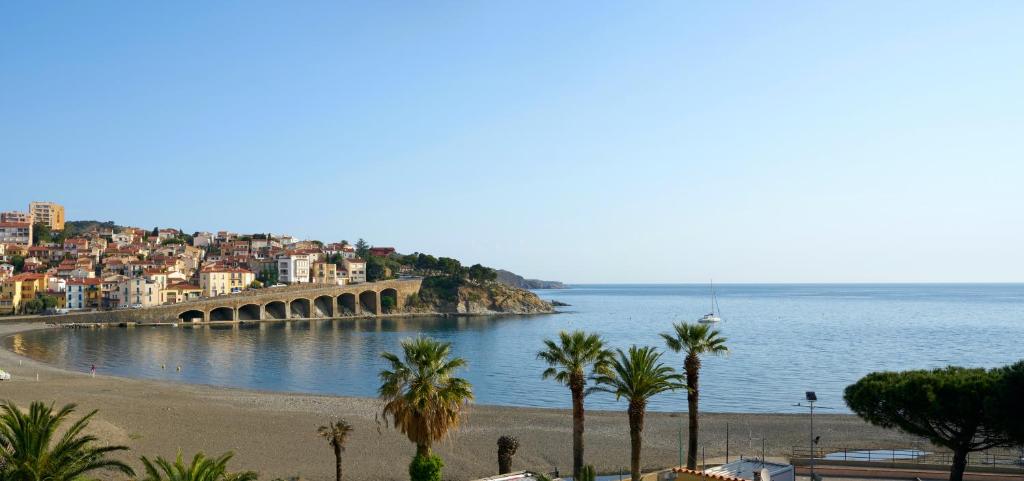 a view of a beach with palm trees and a bridge at Vue Mer Panoramique Exceptionnelle l T2 Mezzanine Luxueux in Banyuls-sur-Mer