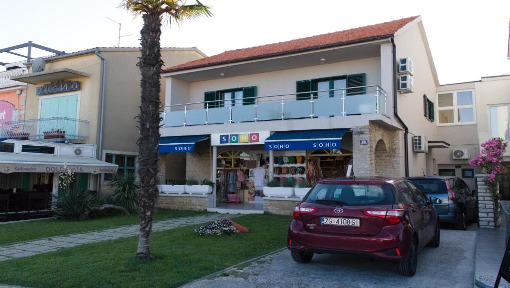 ein rotes Auto, das vor einem Gebäude parkt in der Unterkunft Villa Koraljka in Vodice