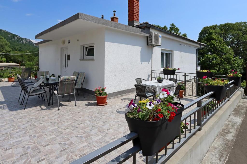 eine Terrasse mit einem Tisch und Blumen auf einem Zaun in der Unterkunft Apartments with a parking space Bribir, Novi Vinodolski - 19862 in Bribir