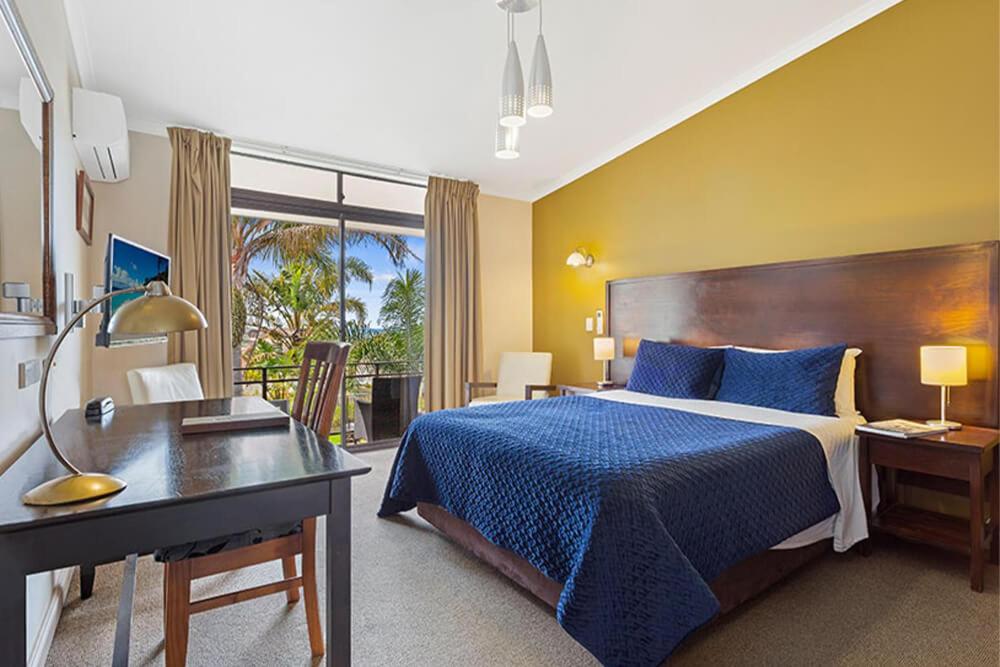 um quarto de hotel com uma cama e uma secretária e uma cama sidx sidx em The Whale Inn em Narooma