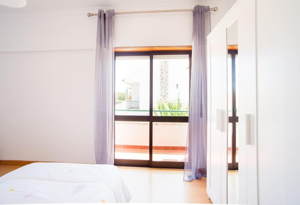 a bedroom with a bed and a large window at Sunny Marisol T2 in Aroeira
