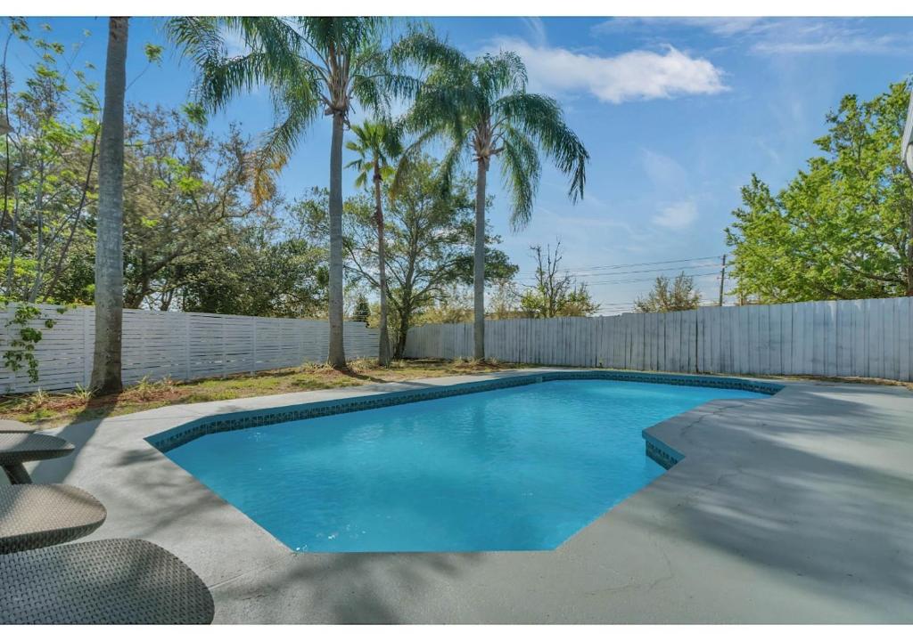 a swimming pool in a backyard with a fence and palm trees at The Cozy spot in Orlando