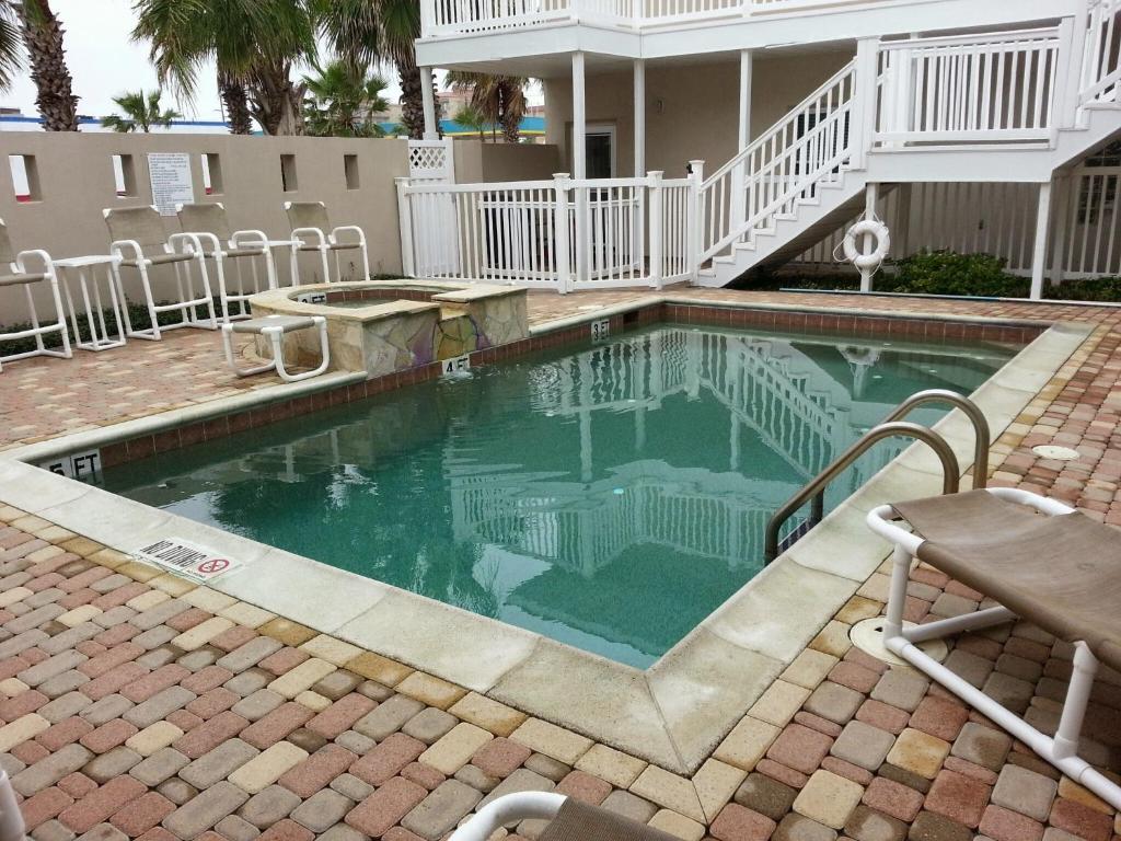 a swimming pool with chairs and a house at Los Cabos III Condominiums in South Padre Island