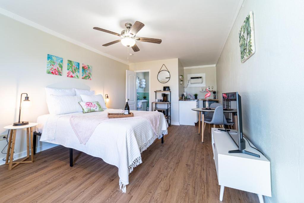 a bedroom with a white bed with a ceiling fan at Renovated Studio - Steps to Beach, POOL, & Cabana! in Panama City Beach