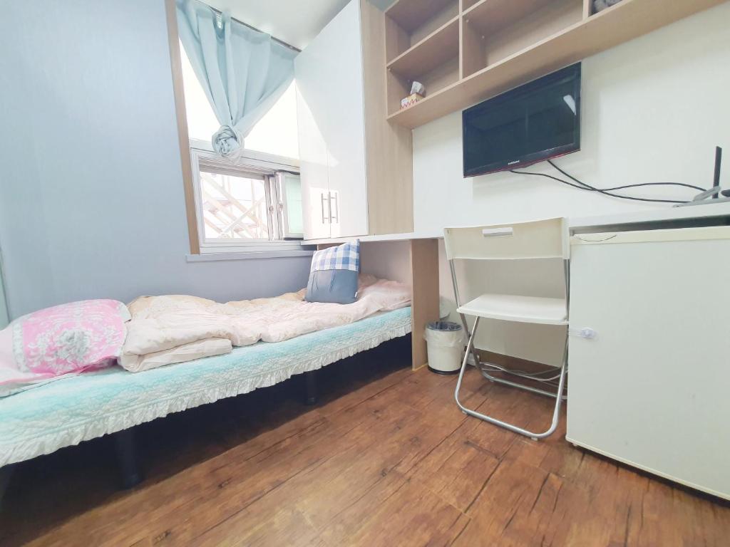 um pequeno quarto com uma cama e uma televisão em Apgujeong Home em Seul