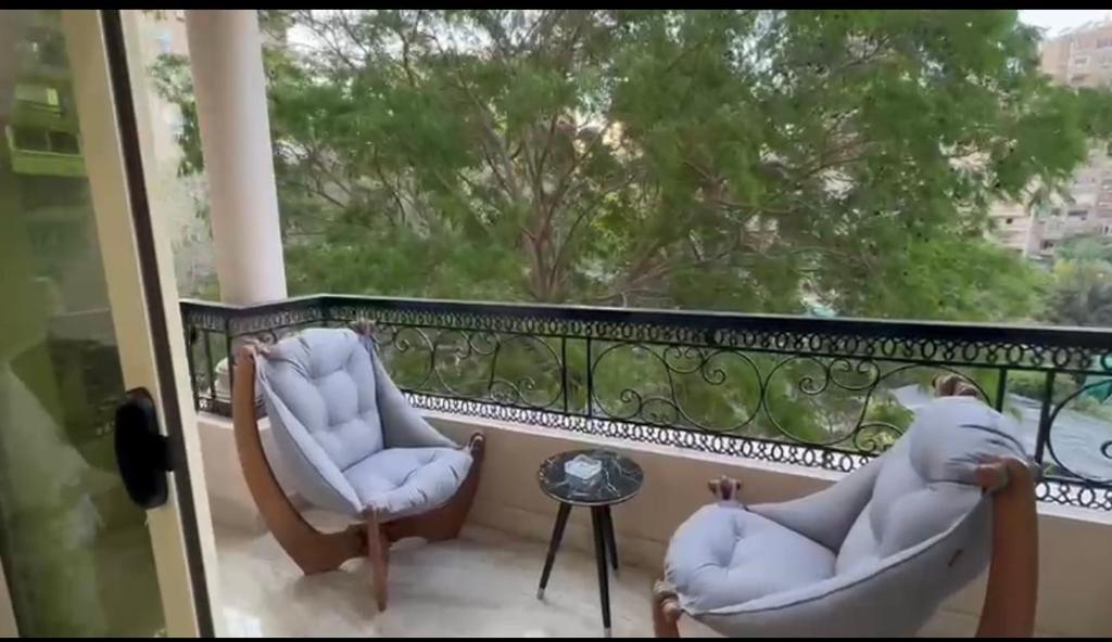 a balcony with two chairs and a table at شقة راقية فندقية فرش جديد عمارة فندقيه المهندسين الجيزة in Cairo