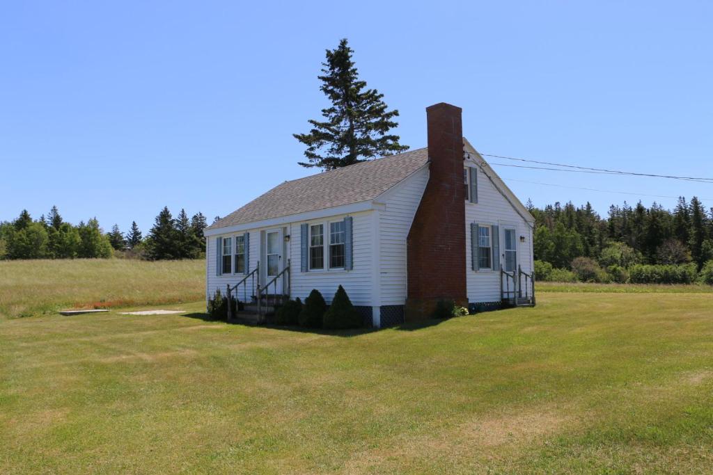 una pequeña casa blanca con chimenea en un campo en Point Field en Deer Isle