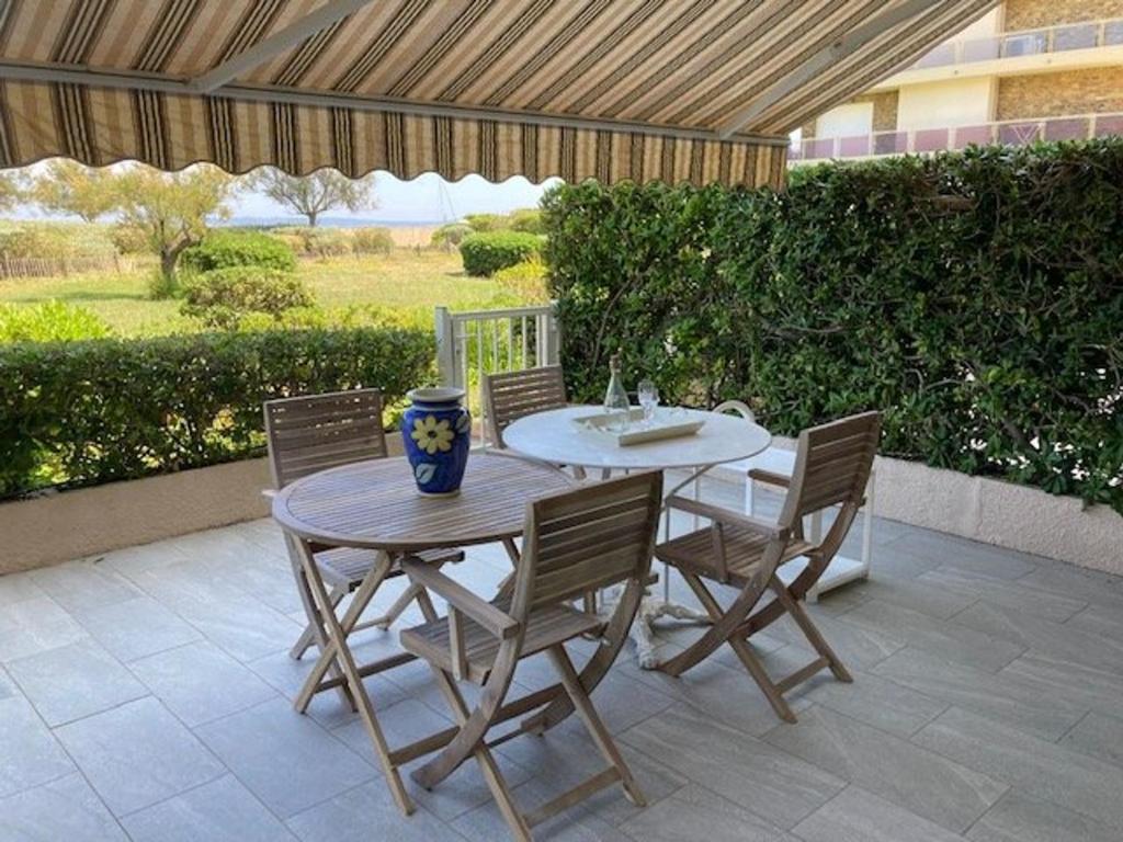 - une table et des chaises sur une terrasse avec un parasol dans l'établissement Appartement climatisé en bord de mer, Le Lavandou - FR-1-308-181, au Lavandou