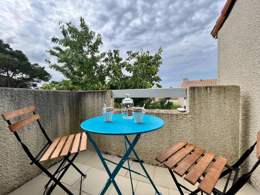 une table bleue et deux chaises sur la terrasse dans l'établissement Appartement Dolus-d'Oléron, 2 pièces, 4 personnes - FR-1-246A-253, à Dolus-d'Oléron