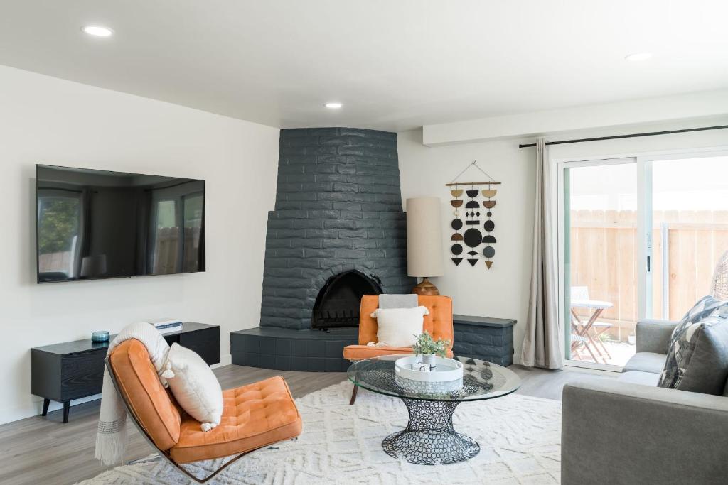 sala de estar con chimenea de piedra y sillas de color naranja en The Rosemont III - La Jolla Luxury en San Diego