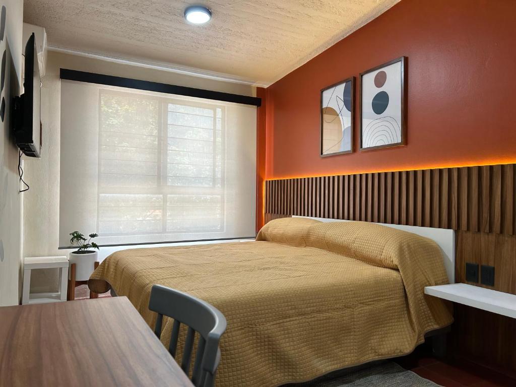 a bedroom with orange walls and a bed and a table at Xochimilco Apartment in Oaxaca City