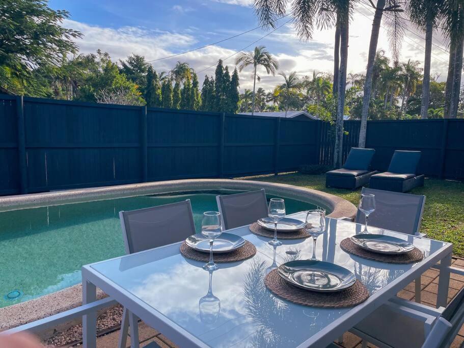 a white table with wine glasses on it next to a pool at Port Douglas Beach Cottage in Port Douglas