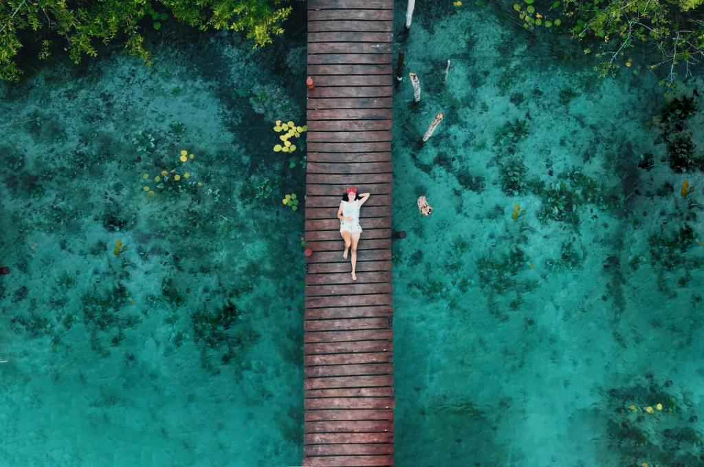 an overhead view of a woman walking on a wooden boardwalk at Bluebayou Bacalar in Bacalar