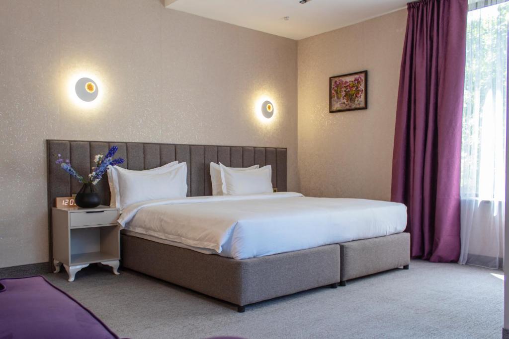 a bedroom with a large bed with white pillows at Orient Hotel Bishkek in Bishkek