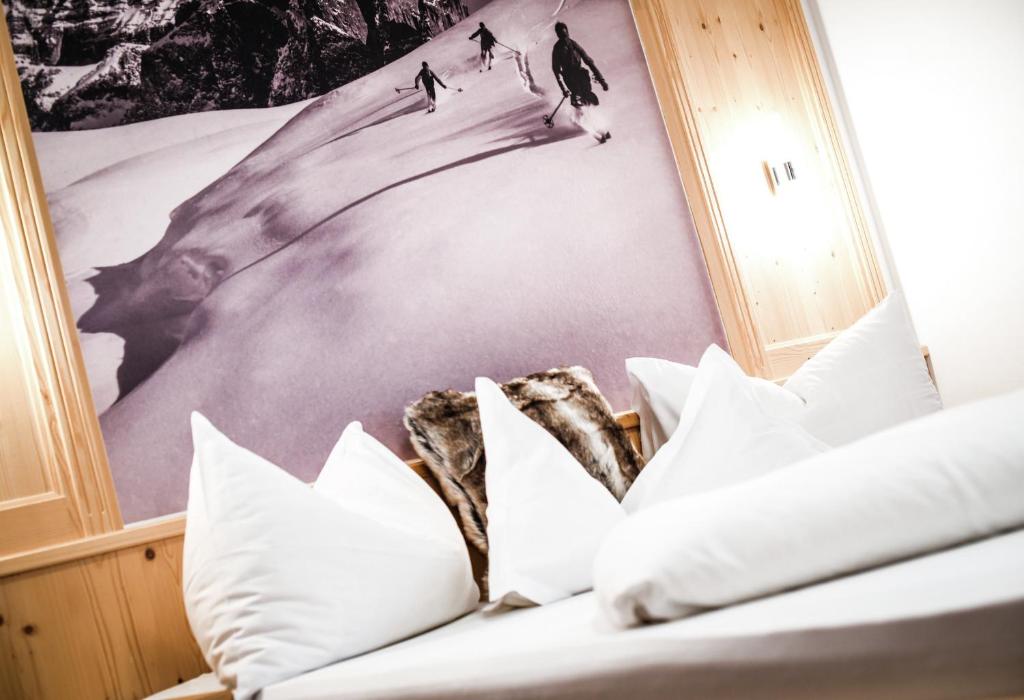 Una cama con almohadas y una foto de gente esquiando. en Apartments Sunela, en Selva di Val Gardena
