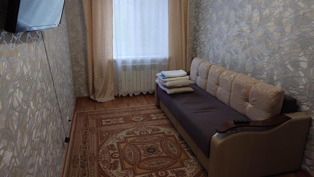 ein Sofa in einem Zimmer mit einem Fenster und einem Teppich in der Unterkunft Конгресс in Petropawlowsk