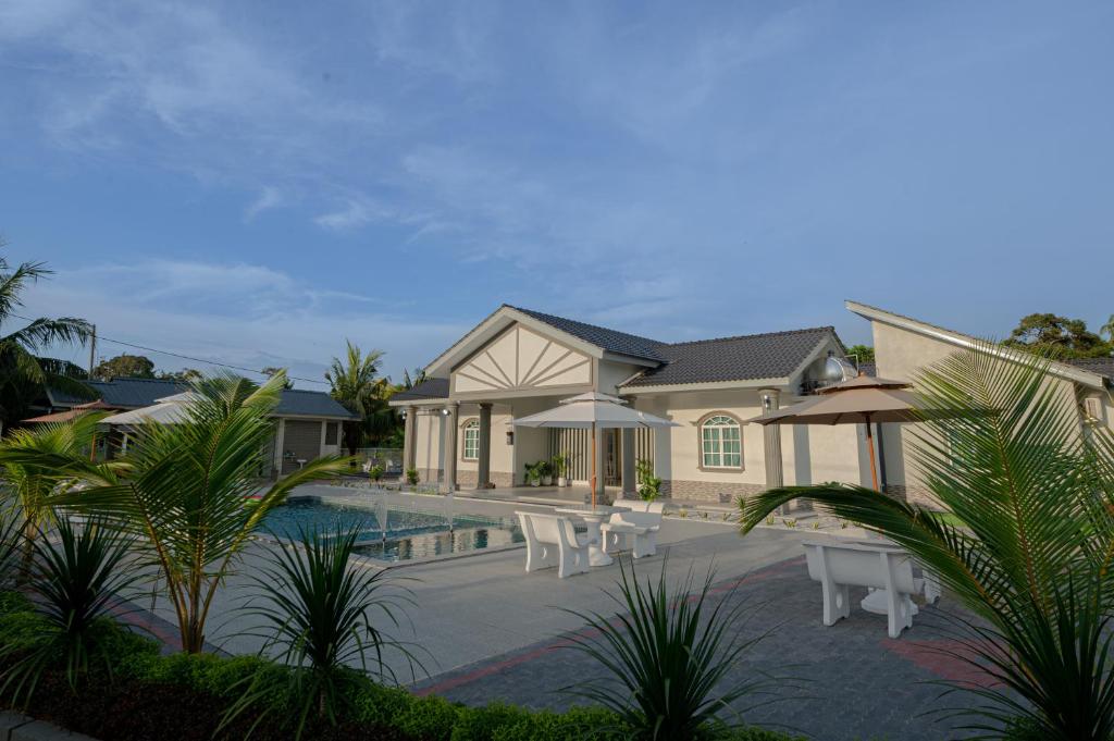 a house with a swimming pool with chairs and umbrellas at Villa Dracaena Melaka With Swimming Pool, Hill View and 20 minutes to Town in Melaka