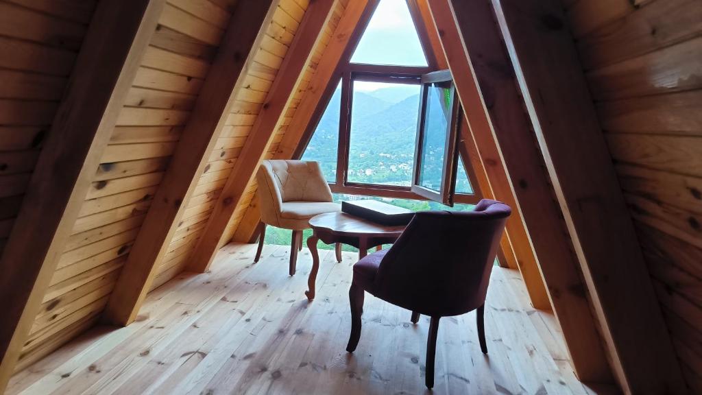 mesa y sillas en una habitación con ventana grande en Tutaste Bungalov, en Arhavi