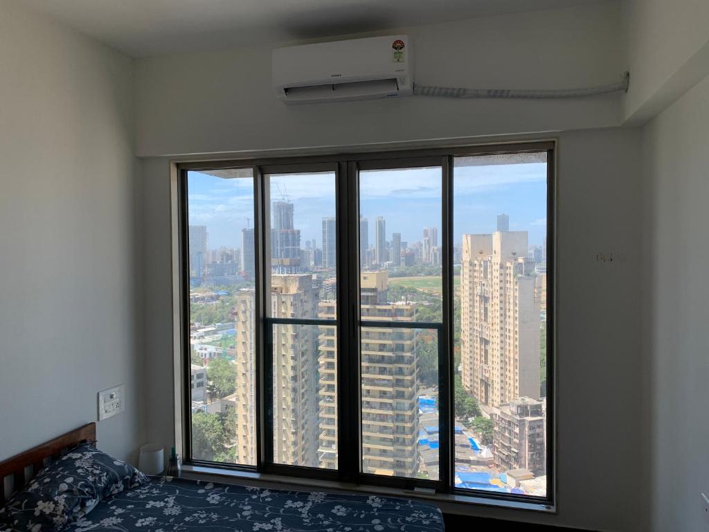 a bedroom with a large window with a view of a city at Room in Flat with Amazing City and Sea View in Mumbai